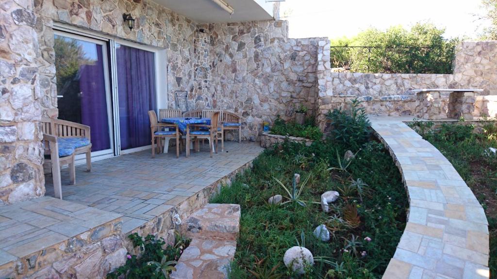 a patio with a table and chairs and a stone wall at Το πετρινο in Agia Marina Mikrolimanou