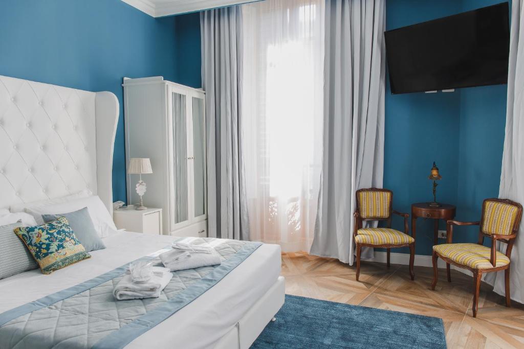 een slaapkamer met een wit bed met blauwe muren en stoelen bij B&B La Residenza di Michelangelo in Florence