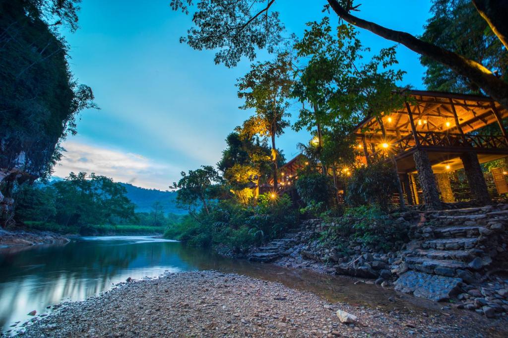 a building next to a river at night at Art's Riverview Lodge in Khao Sok National Park