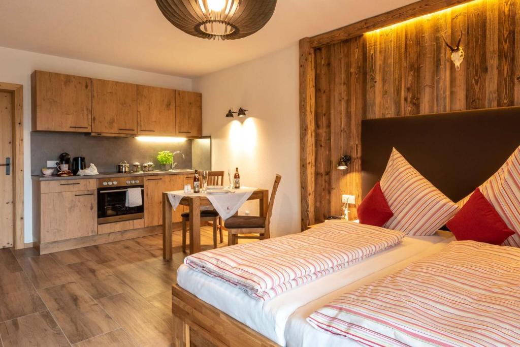 a bedroom with a bed and a table and a kitchen at Pension und Appartements Wild in Otterfing