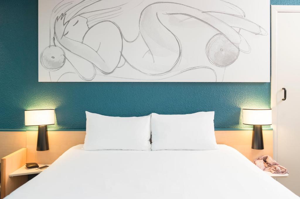 ein Schlafzimmer mit einem Bett mit zwei Lampen und einem Gemälde in der Unterkunft ibis Liège Centre Opéra in Lüttich