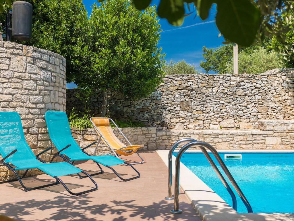 2 chaises et une piscine à côté d&#39;un mur en pierre dans l&#39;établissement Holiday Home Christa by Interhome, à Krnica