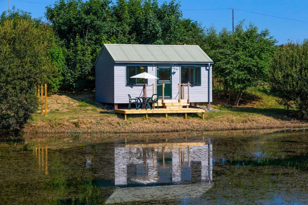 a small house on the edge of a body of water at Lynstone Lakes in Bude