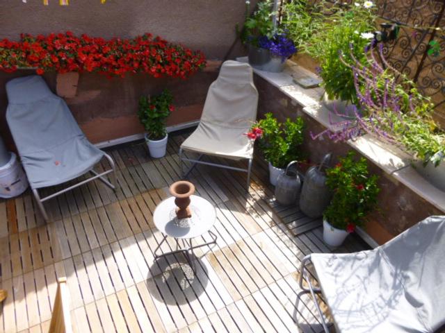 a patio with two chairs and flowers and plants at La Parenthèse - toit terrasse in Die