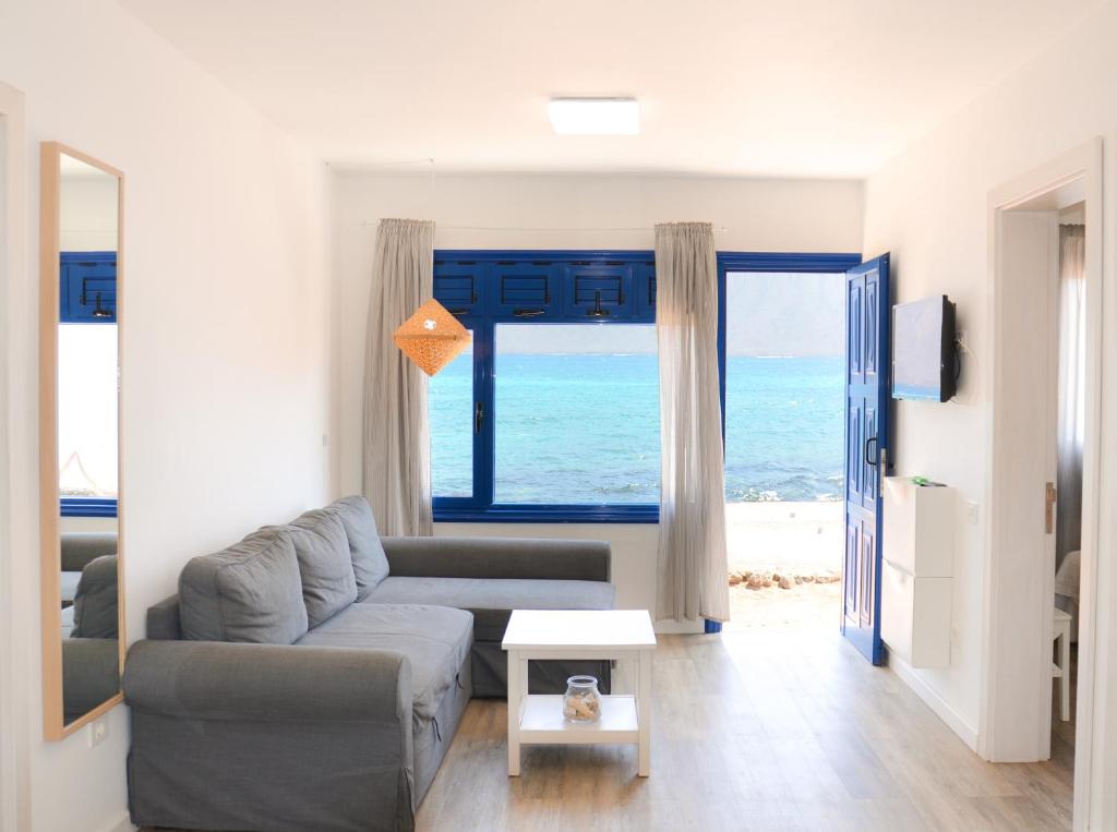 ein Wohnzimmer mit Couch und Blick aufs Meer in der Unterkunft Apartamentos El Marinero - Caletilla in Caleta de Sebo