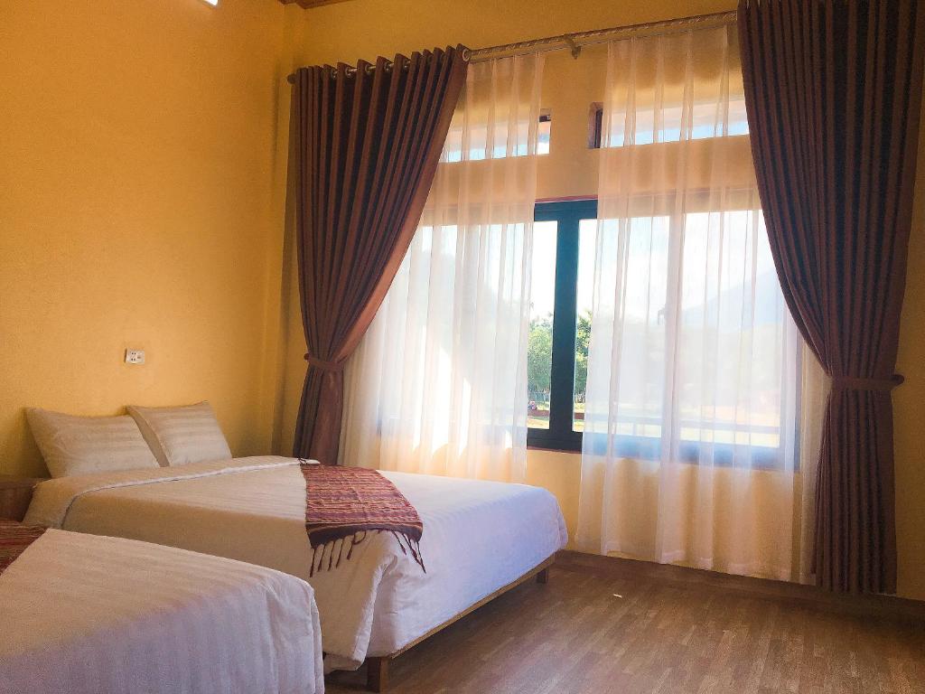 a bedroom with two beds and a large window at Mai Chau Xanh Bungalow in Mai Chau