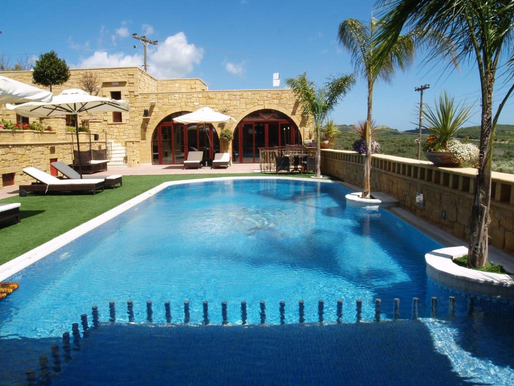 une grande piscine bleue dans une cour avec des palmiers dans l'établissement Palazzo Loupassi Boutique Villas, à Vasilópoulon