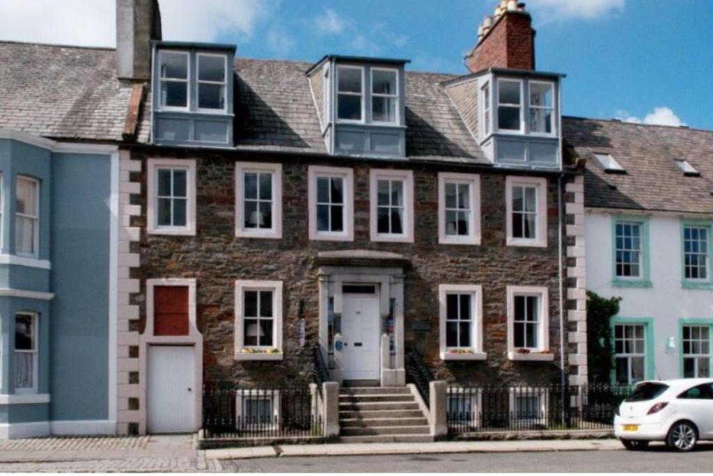 a brick house with a white car parked in front of it at Gladstone House in Kirkcudbright