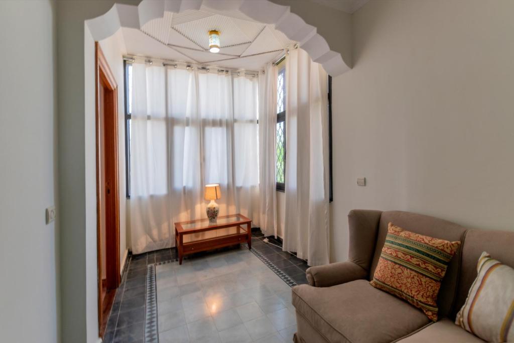 a living room with a couch and a large window at Hôtel Riad Airport Marrakech in Marrakech