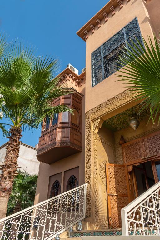 a house with a palm tree in front of it at Hôtel Riad Airport Marrakech in Marrakech