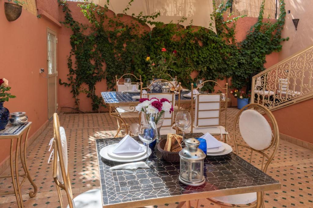 a table with plates and flowers on top of it at Hôtel Riad Airport Marrakech in Marrakech