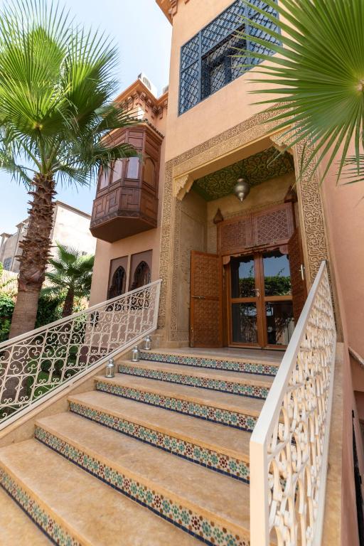 a house with stairs and a palm tree at Hôtel Riad Airport Marrakech in Marrakech
