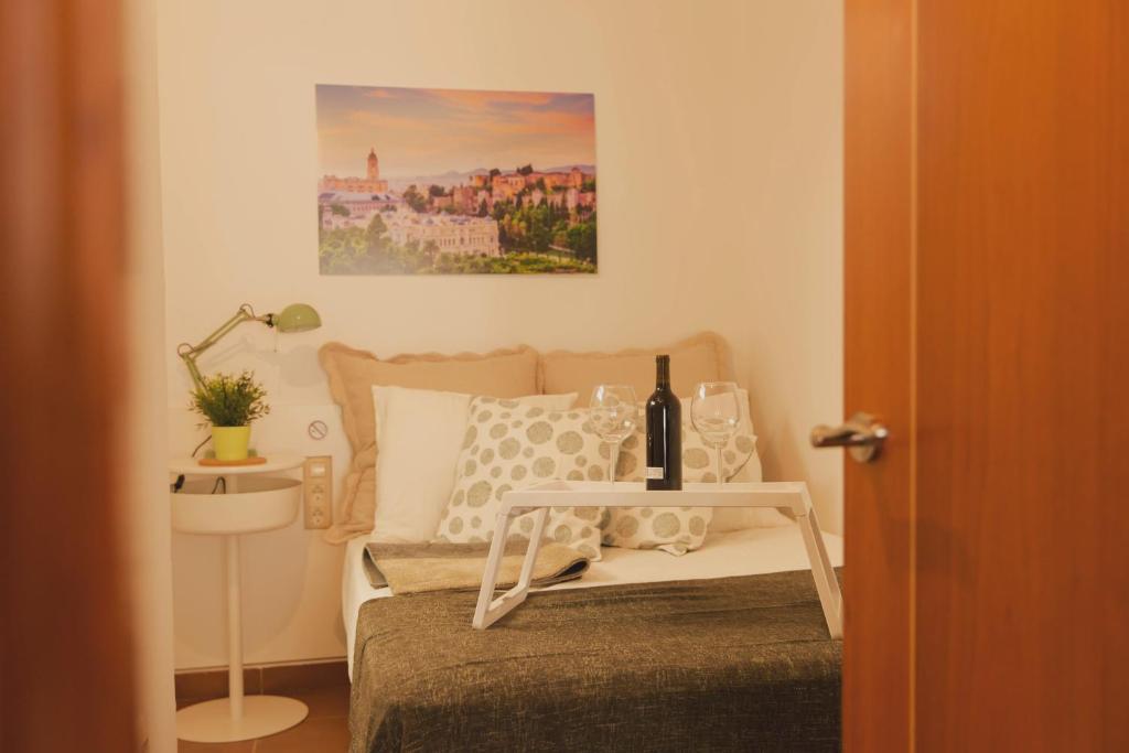 a bedroom with a bed and a table with a bottle of wine at Estancia de Invitados de Casa Tais in Málaga
