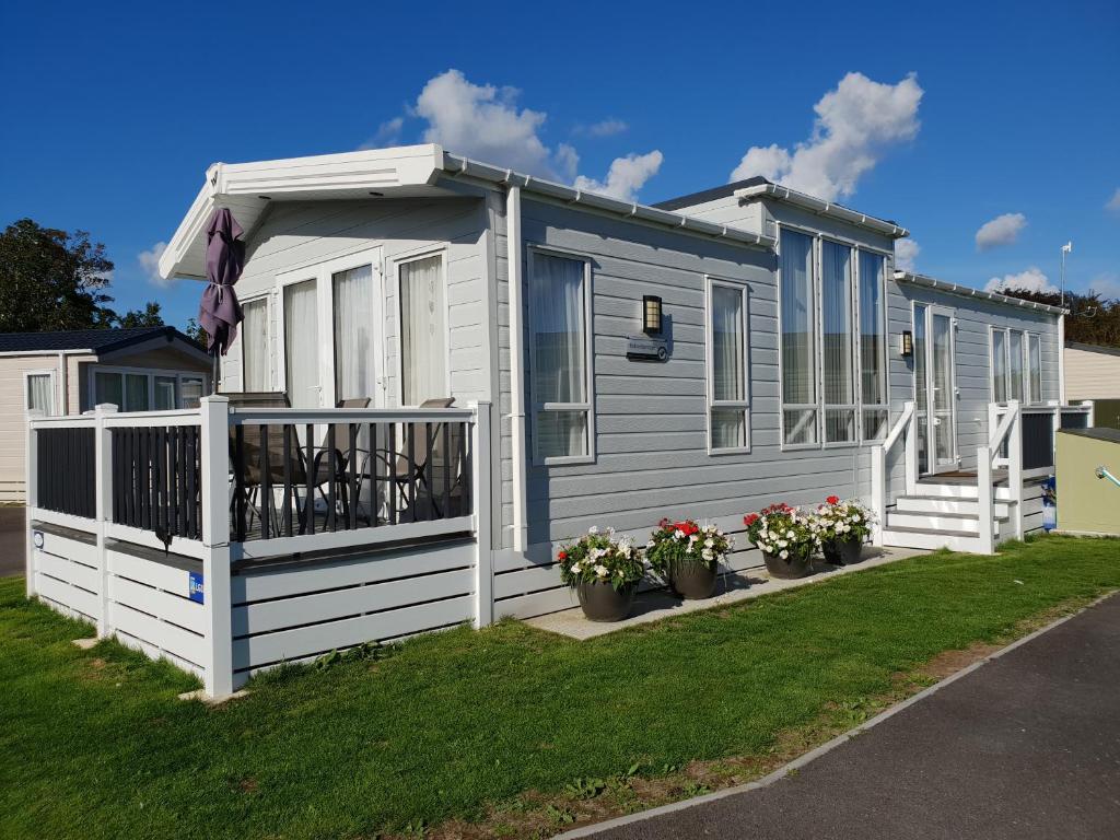 a tiny house with a porch and flowers in a yard at Kent Getaways in Westgate-on-Sea