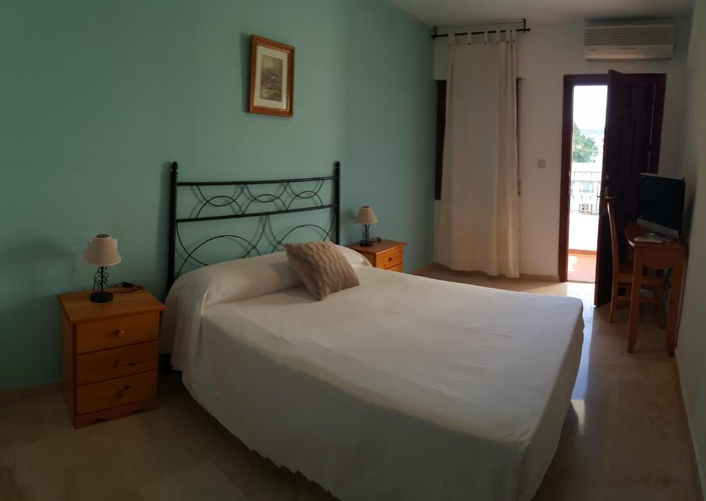 a bedroom with a large white bed and a television at Hotel Casabermeja in Casabermeja