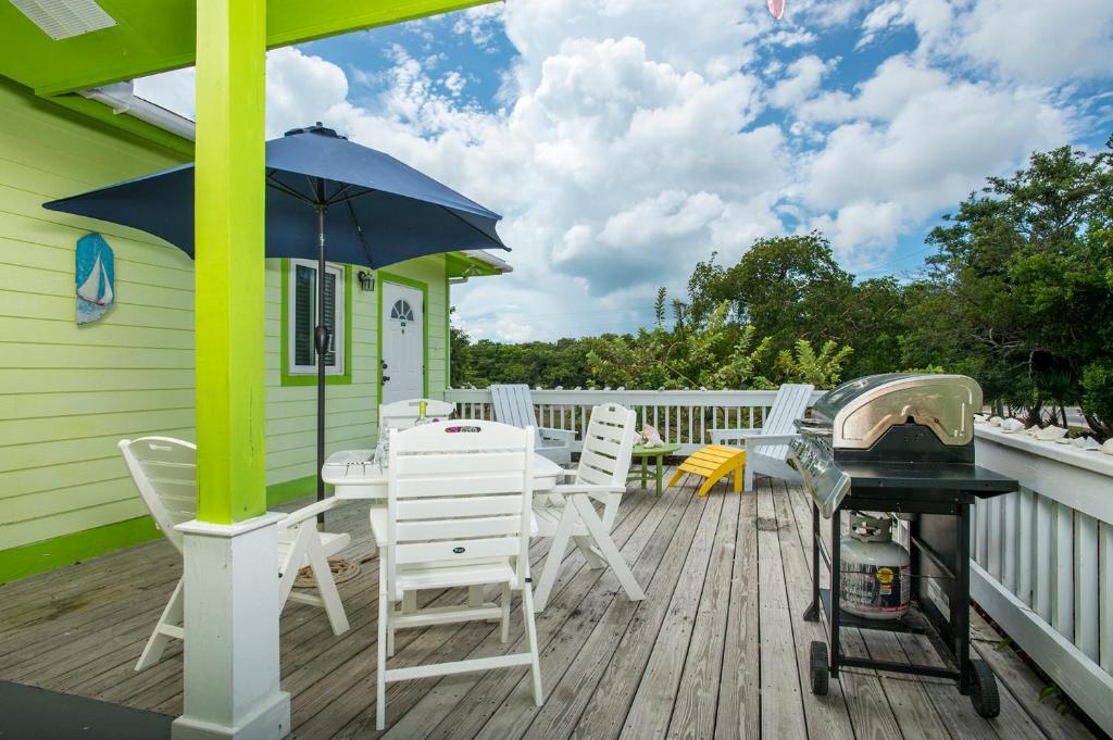 una terraza con mesa, sillas y sombrilla en Sir Charles Guest House, en South Palmetto Point