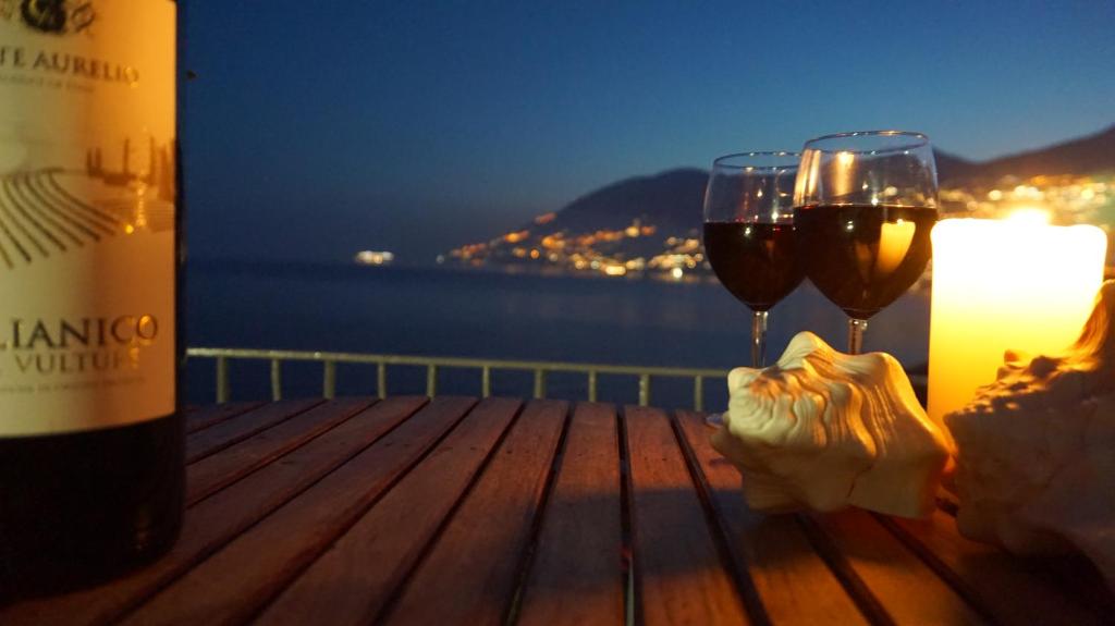 マイオーリにあるVilla The Cliffの木製テーブルの上に置かれたワイン2杯とキャンドル