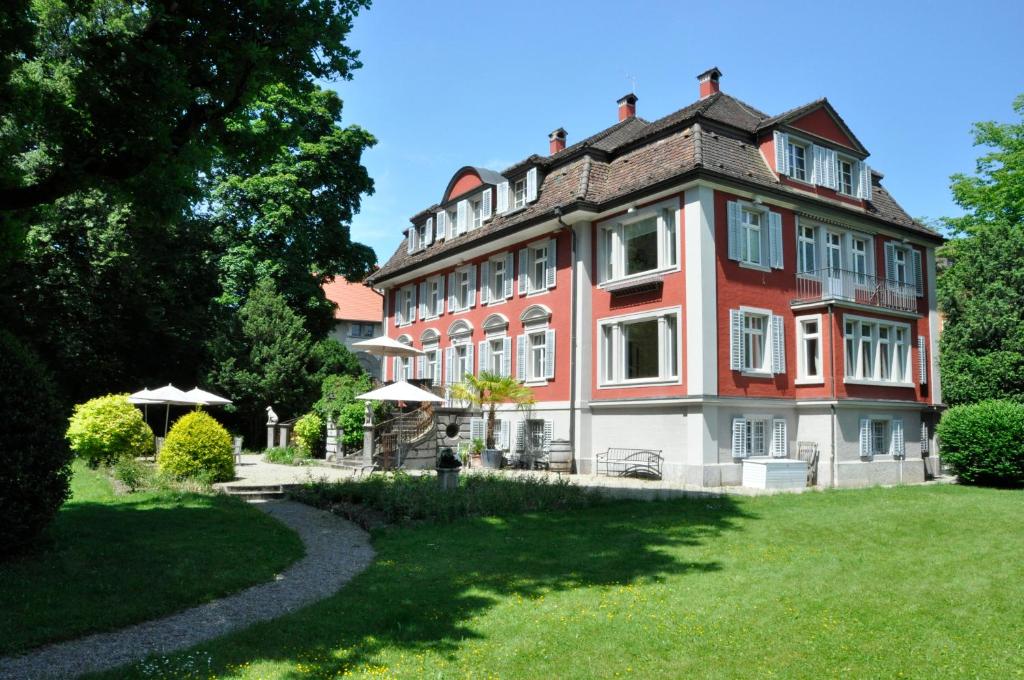 un grand bâtiment rouge et blanc avec une cour herbeuse dans l'établissement Villa Jakobsbrunnen, à Winterthour