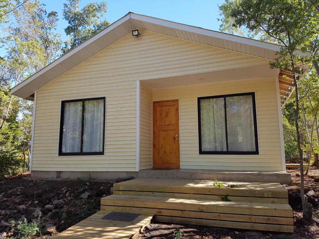 une petite maison jaune avec une porte en bois dans l'établissement Cabañas Siete Tazas, à Molina