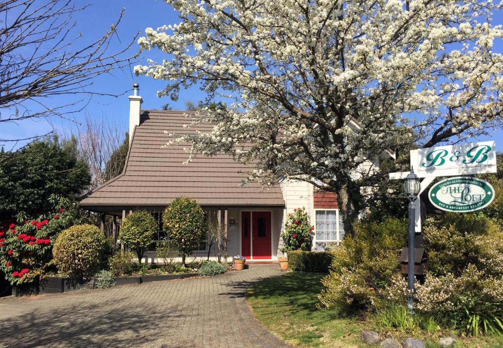 dom z kwitnącym drzewem i znakiem ulicznym w obiekcie The Loft Bed and Breakfast w mieście Taupo