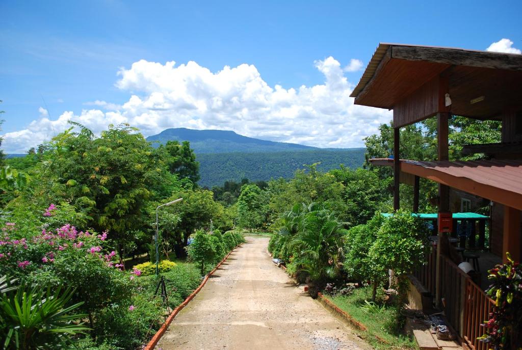 uma estrada de terra ao lado de uma casa com montanhas ao fundo em Prue Sa Raj em Phetchabun