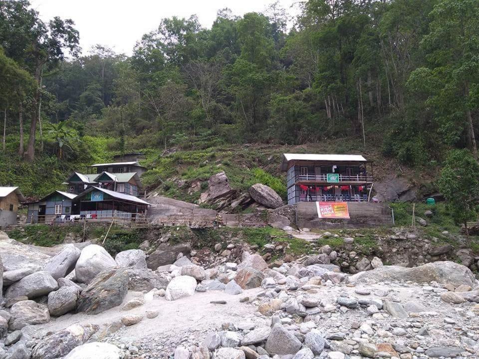a group of houses on a hill next to a river at Vamoosetrail Reshi River Cottage in Pedong