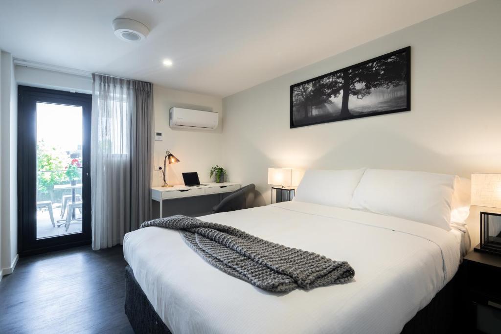 Ascot Budget Inn & Residences في بريزبين: غرفة نوم بسرير ابيض كبير ونافذة
