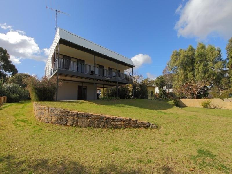 a large house with a stone wall in a field at Relax where the river meets the ocean in Guilderton