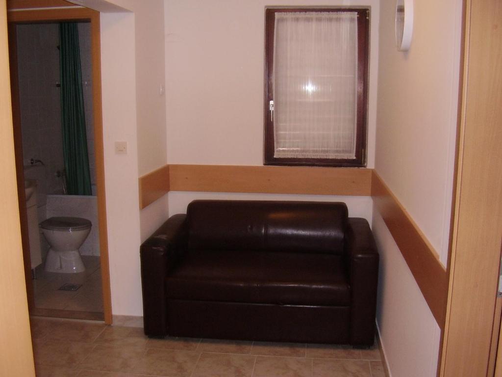 a brown leather couch in a room with a window at Apartments Meni in Drage