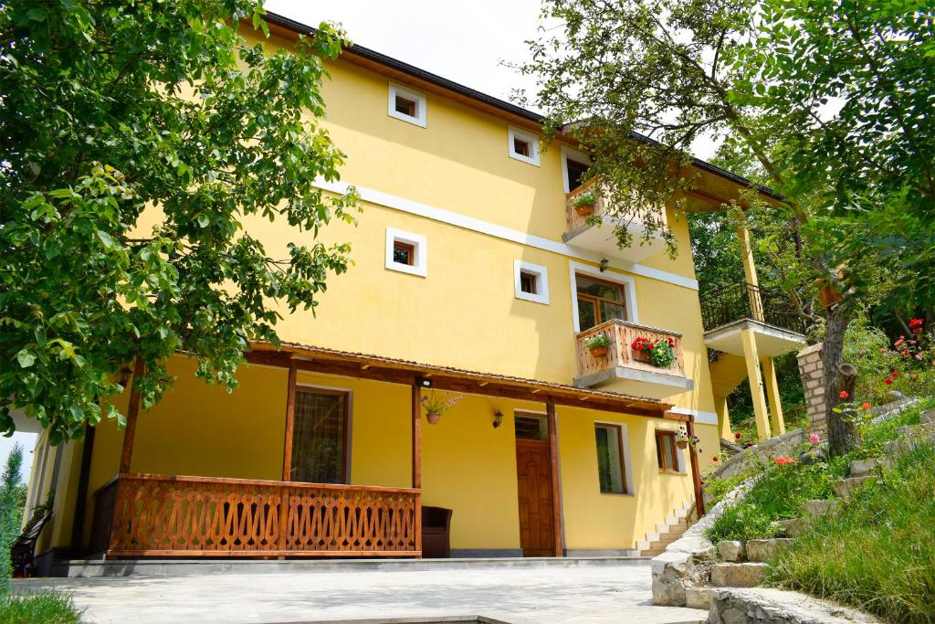 a yellow house with a porch and a balcony at Verin Tun in Dilijan