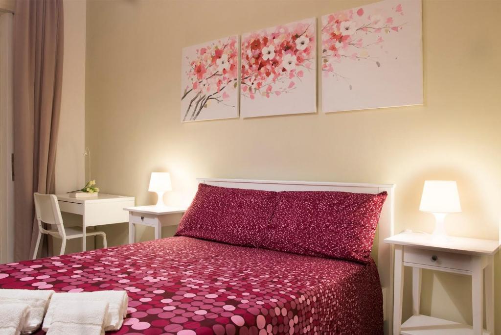 a bedroom with a red bed with three paintings on the wall at Tanzi Home in Bari