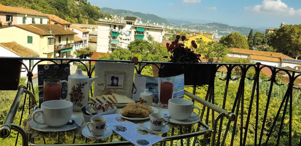 einen Tisch mit Tassen und Teller mit Speisen auf einem Balkon in der Unterkunft a casa di nonna Elza in La Spezia