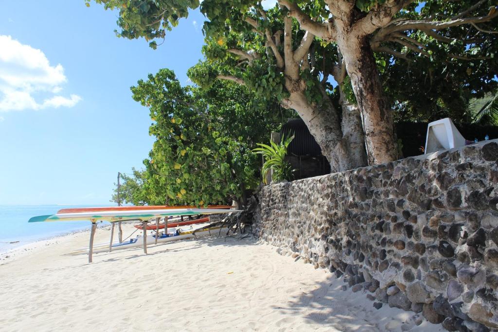 a table and surfboards on a beach next to a wall at Fare Edith Moorea in Haapiti
