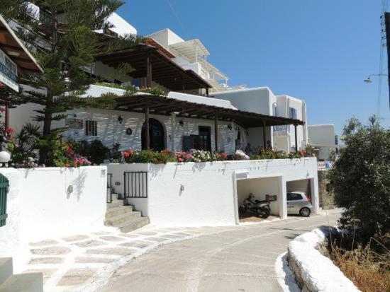 a white building with a car parked in front of it at Studios Flora Manos in Platis Gialos