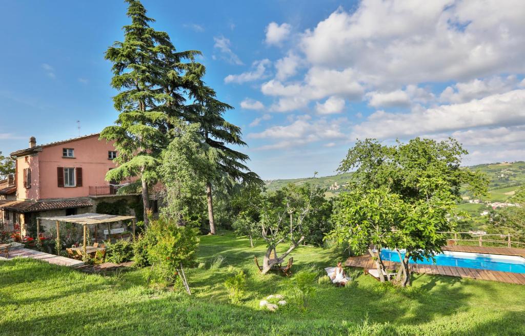 a house with a large tree and a pool at Bacialupo Foresteria in Montecalvo Versiggia