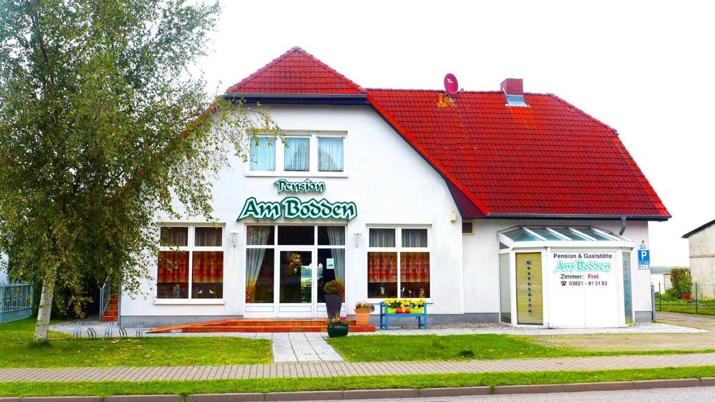 a white building with a red roof at Pension Am Bodden in Ribnitz-Damgarten