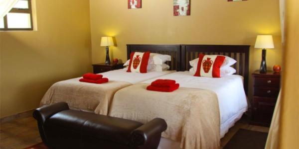 een slaapkamer met twee bedden met rode kussens erop bij Aloe View Rock Lodge in Hluhluwe