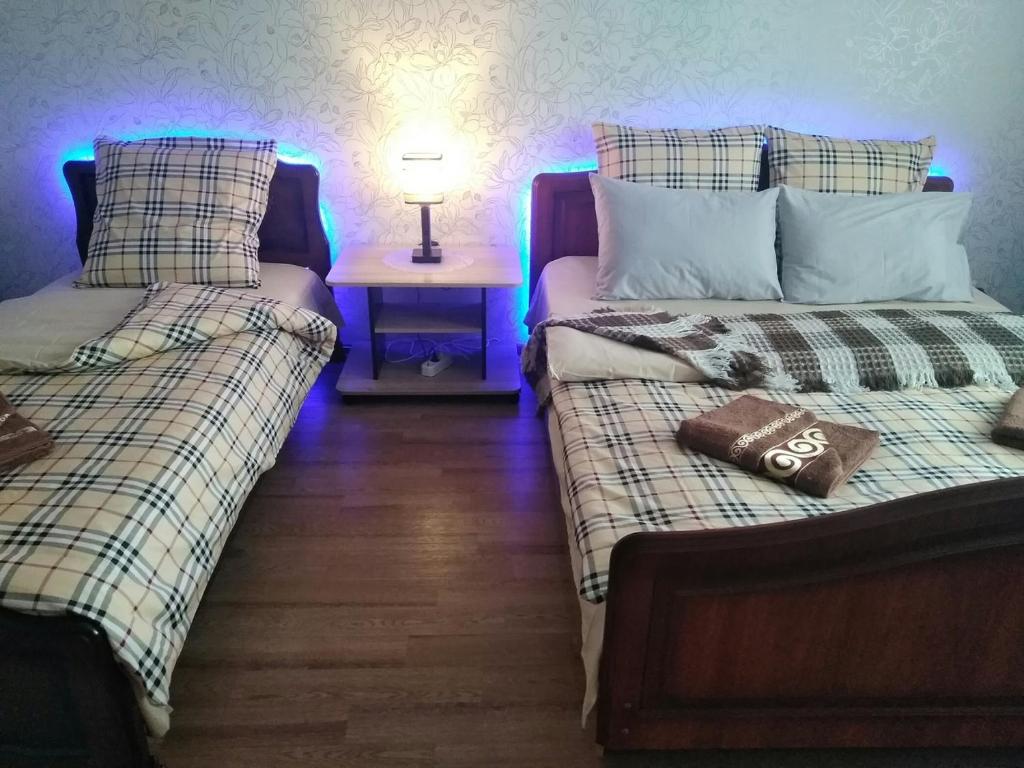トヴェリにあるАпартаменты Тверичанка на Озёрной 7/2のベッド2台、ランプ1台、テーブルが備わる客室です。