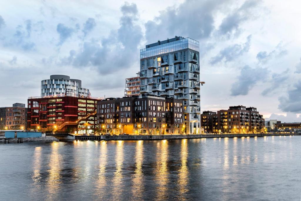 a tall building next to a river with buildings at STAY Seaport in Copenhagen