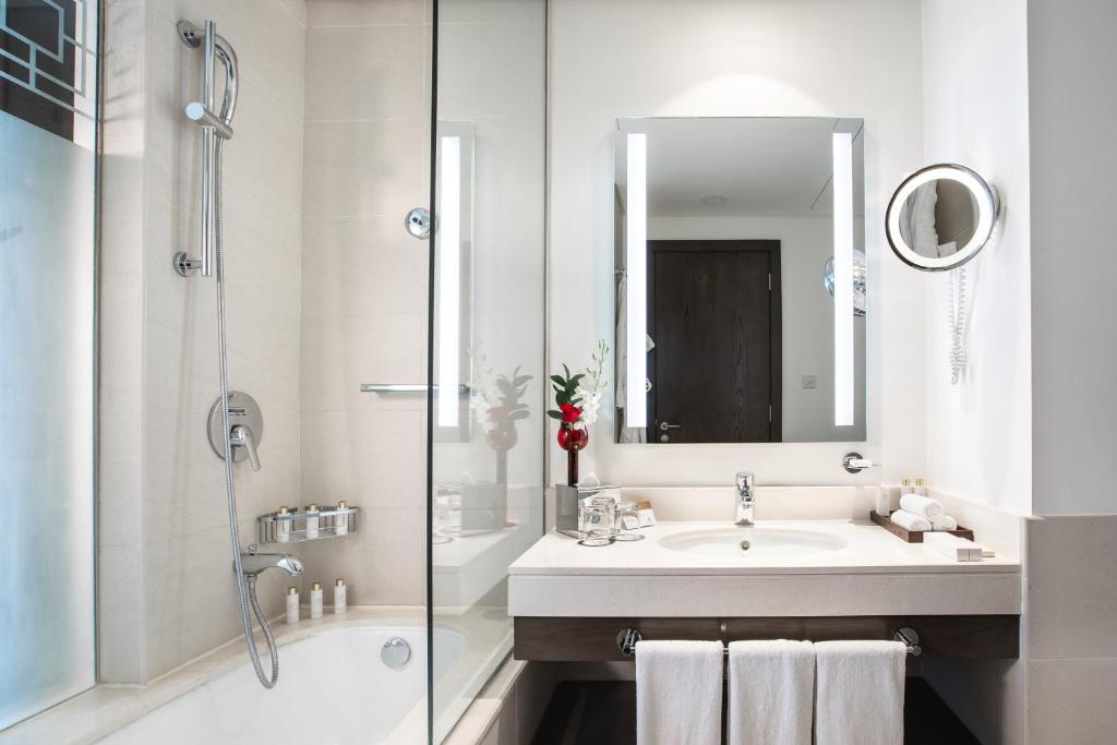 a white bathroom with a sink and a shower at Royal M Hotel Fujairah by Gewan in Fujairah