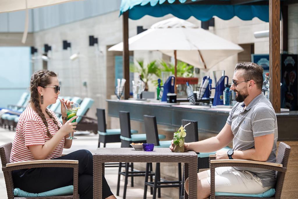 a man and woman sitting at a table in an outdoor cafe at Royal M Hotel Fujairah by Gewan in Fujairah