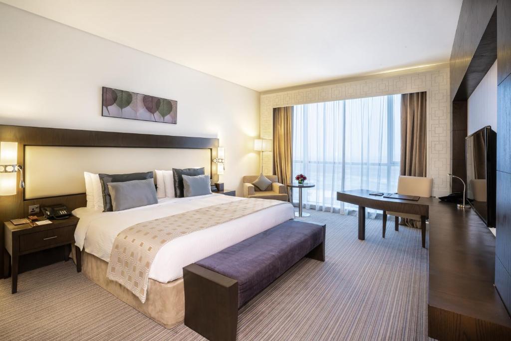 a hotel room with a large bed and a desk at Royal M Hotel Fujairah by Gewan in Fujairah