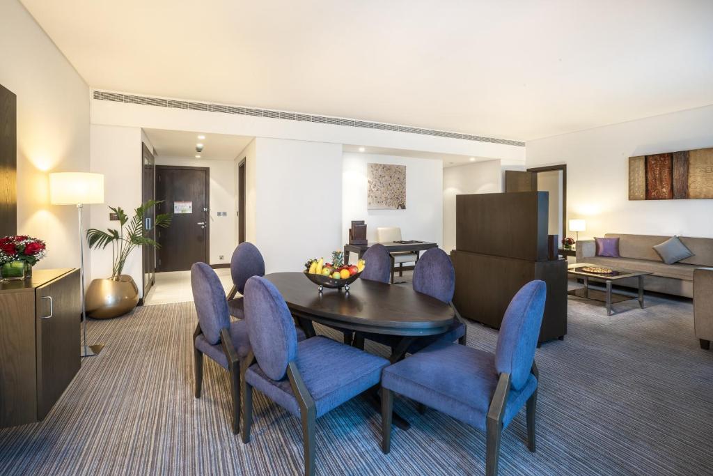 a living room with a table and blue chairs at Royal M Hotel Fujairah by Gewan in Fujairah