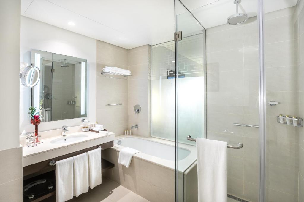 a bathroom with a tub and a sink and a shower at Royal M Hotel Fujairah by Gewan in Fujairah