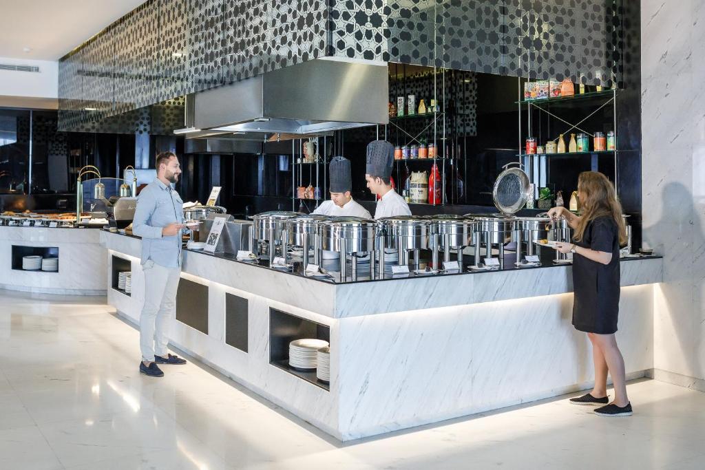 a group of people standing at a counter in a kitchen at Royal M Hotel Fujairah by Gewan in Fujairah