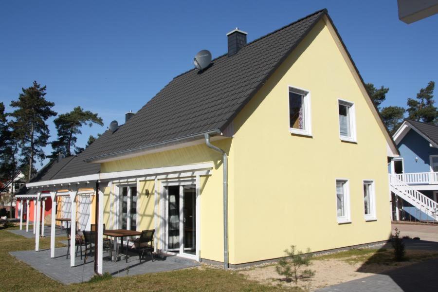une maison jaune avec un toit noir et une table dans l'établissement K 97 - stilvolles Ferienhaus mit Kamin & WLAN am See in Röbel an der Müritz, à Röbel