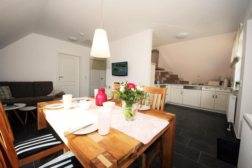 a kitchen and living room with a wooden table with flowers at K 102 OG - stilvolle Ferienwohnung an der Müritz in Röbel an der Müritz in Marienfelde