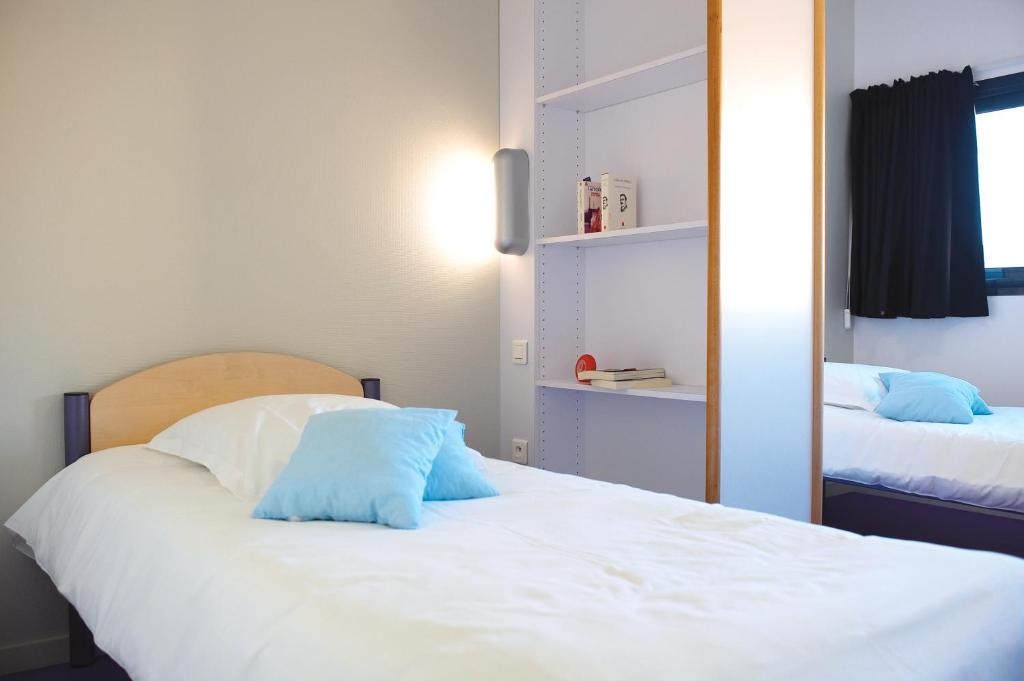 Un dormitorio con una cama blanca con almohadas azules. en JF Accueil &amp; Formation, en Cholet