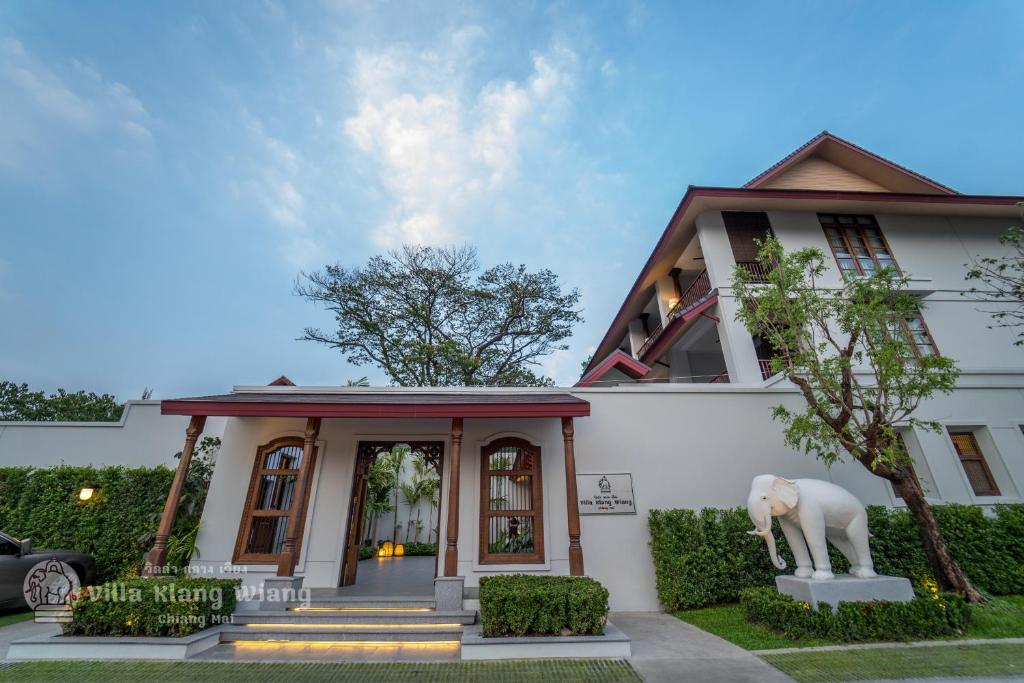 Uma casa branca com uma estátua de elefante à frente. em Villa Klang Wiang em Chiang Mai