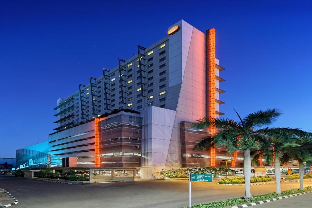 雅加達的住宿－雅加達椰風伽德哈里斯酒店及會議中心，一座高大的建筑,前面有棕榈树